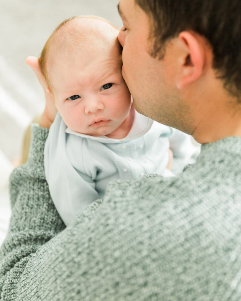 Dad kissing newborn baby's head during a relaxed family newborn session in Montgomery Texas.