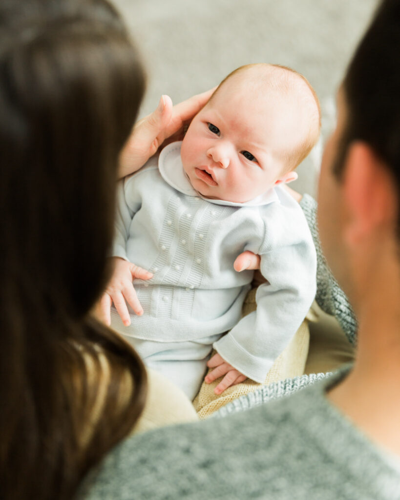 New parents snuggling their newborn son during a relaxed in-home newborn photography session.
