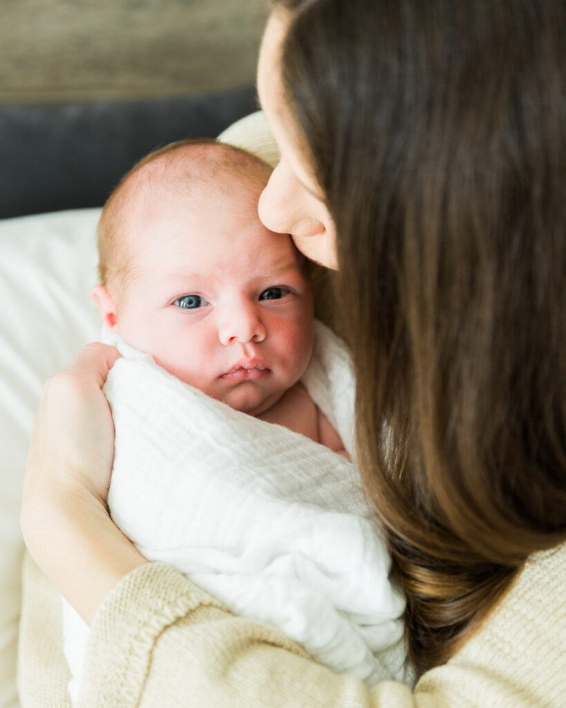 Mother kissing her newborn baby during an in-home newborn photography session in Montgomery TX.