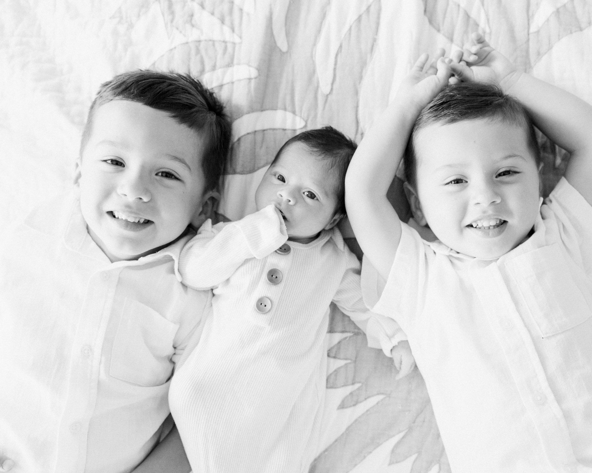 Siblings lying together during an in-home newborn session in The Woodlands TX