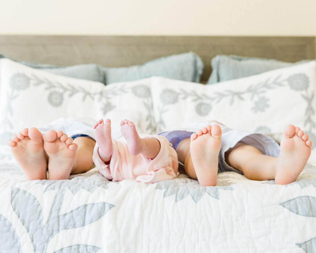 Siblings lying together during an in-home newborn session in The Woodlands TX